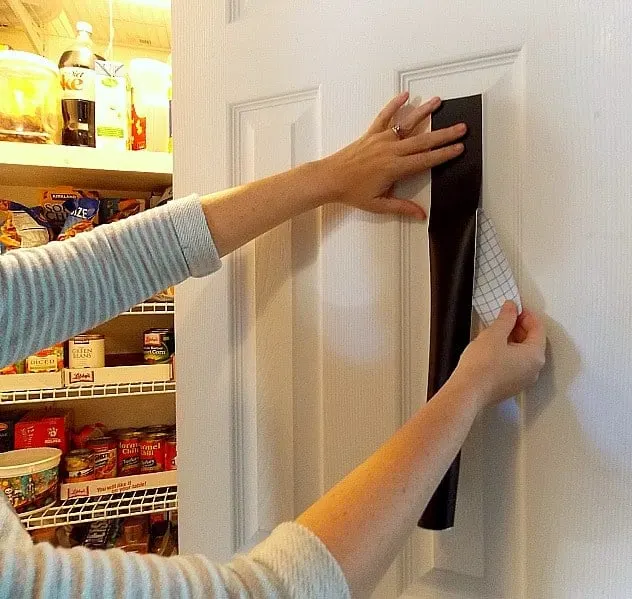 applying chalkboard paper to door of pantry