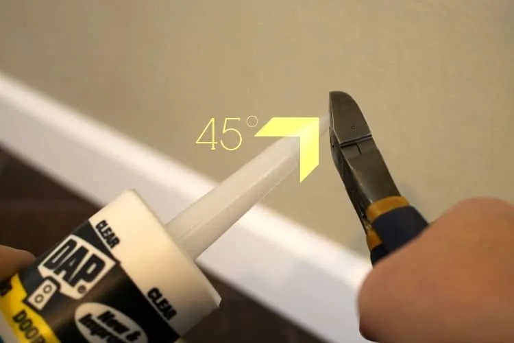 Using wire cutters to cut the tip off a caulk tube at a 45 degree angle