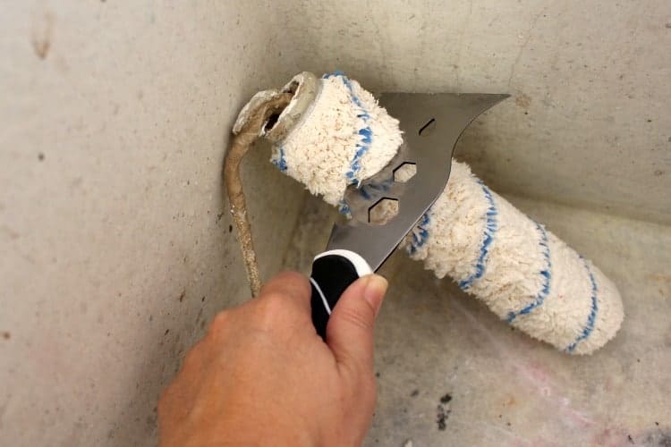 Painter's tool scrapes excess paint off roller