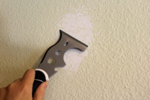 Painter's tool fills in a hole in the wall with spackle.