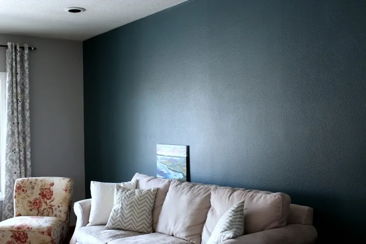 Dark teal wall behind couch, next to gray wall.
