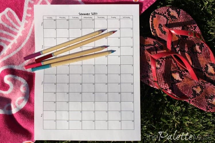 A summer calendar form with colored pencils on a beach towel.