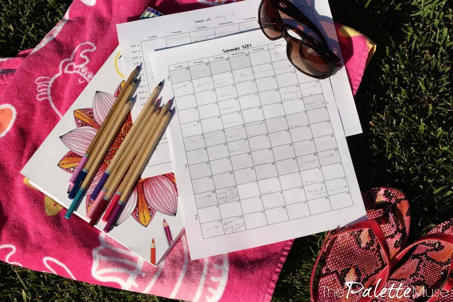 Free printable summer calendars on a beach towel with colored pencils and sunglasses