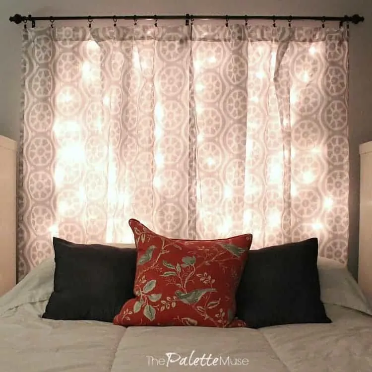 A lit headboard made from curtains and Christmas lights hangs over the bed.