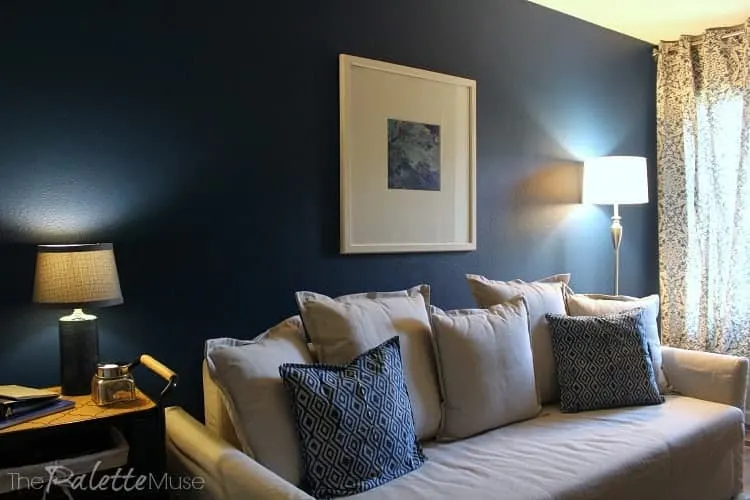 A dark blue accent wall makes this guest room/home office feel cozy and masculine.