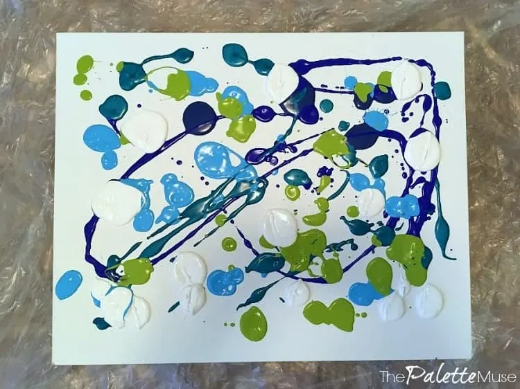 Blobs of blue, green, and white paint on a canvas