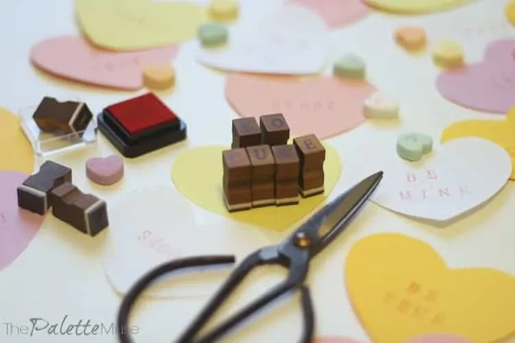 Paper hearts surrounding letter stamps that say "so cute"