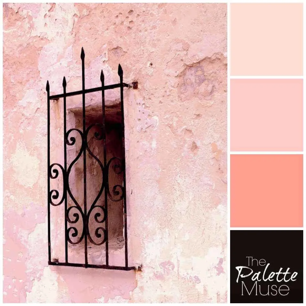 A dark window covered with black wrought iron peeks out of a layered pink plaster wall. #thepalettemuse #pinkpalette #colorinspo