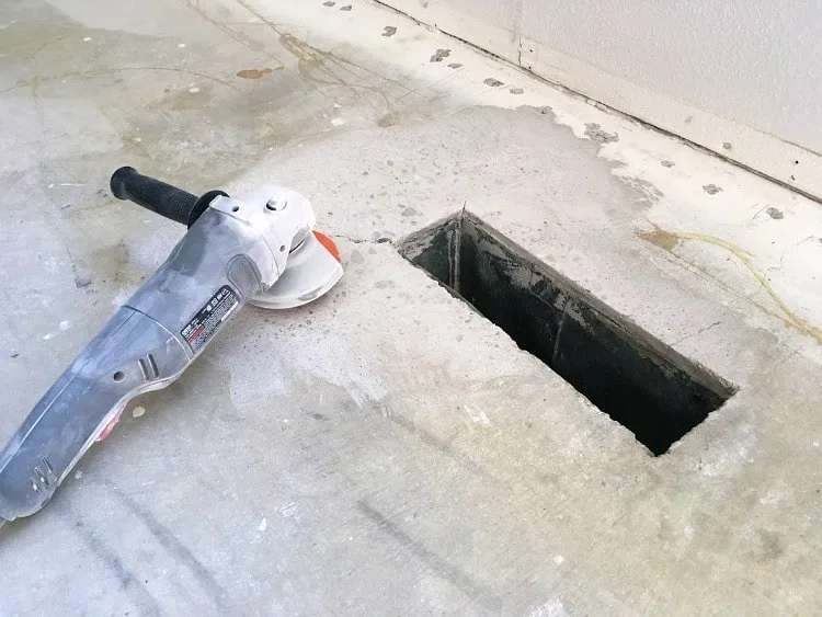 A grinder lays on the concrete near a vent opening