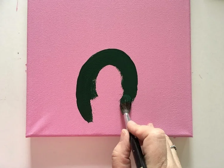 Painting the beginning of a green cactus on a pink background