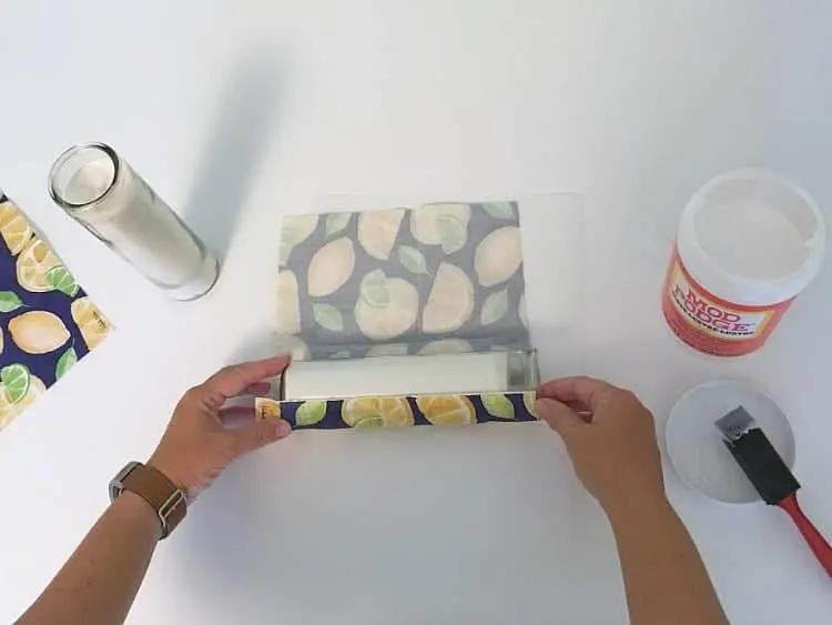 Rolling the napkin onto the candle with glue.