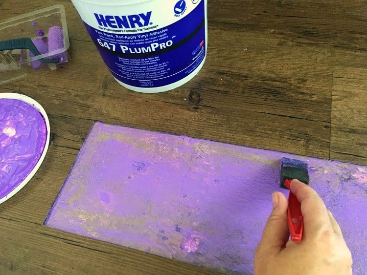 Painting Henry PlumPro glue onto the floor to repair vinyl plank flooring.