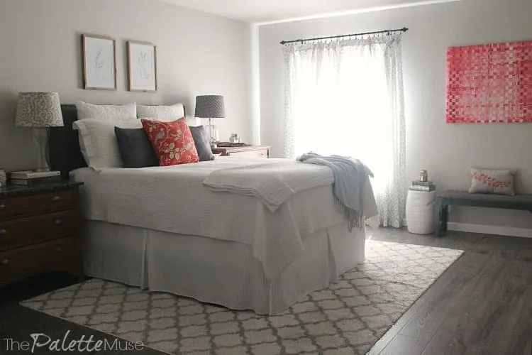 A gray and white bedroom with bright accents of pink and orange.