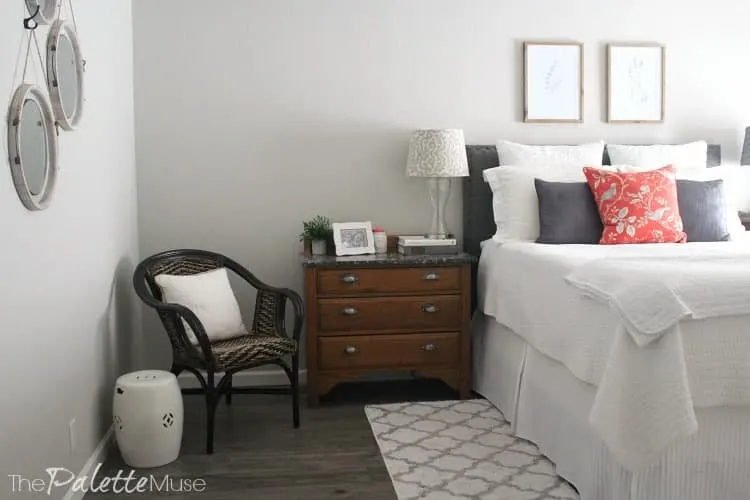 White bedding and wood dresser and chair in the corner of this master bedroom.