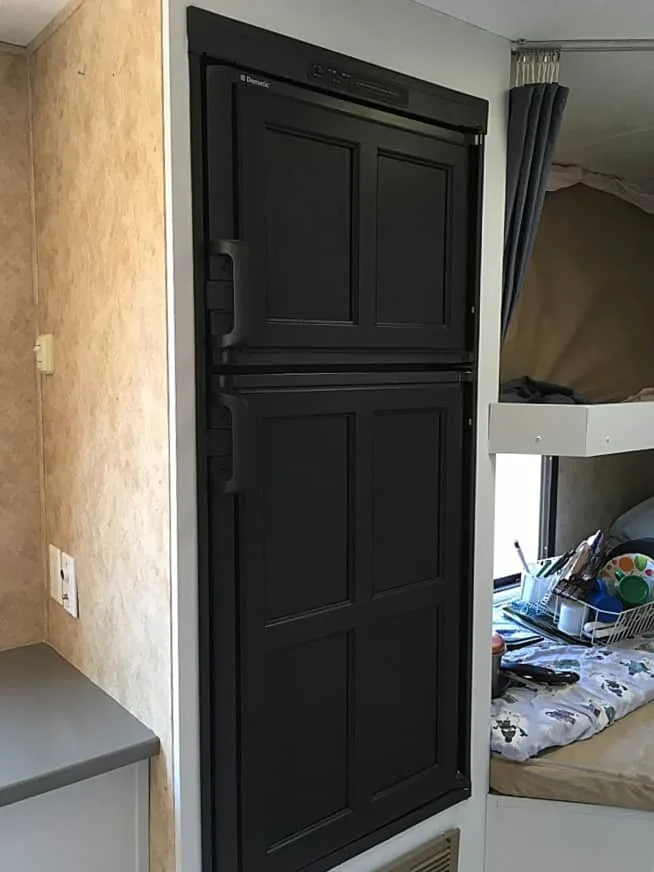 Black painted camper refrigerator.