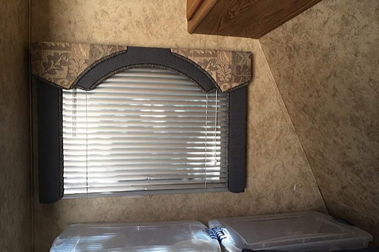 Bed nook in our camper with window and storage bins