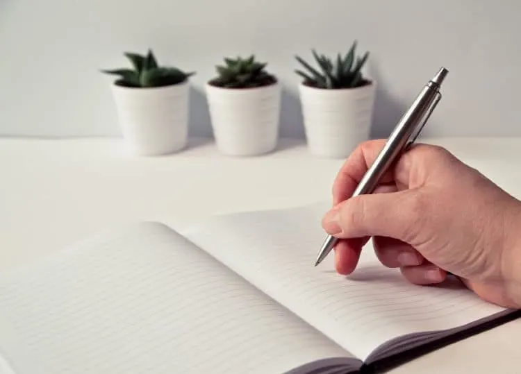 A blank notebook, with a person holding a pen, getting ready to start planning their remodel budget.