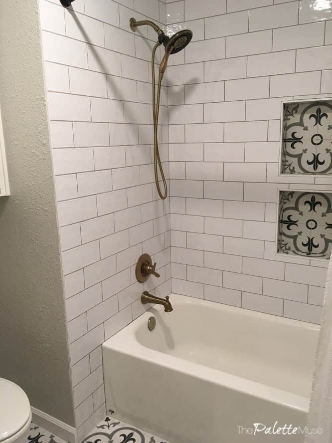 White Bathroom with patterned tile floor and shower niches, and brass shower fixture
