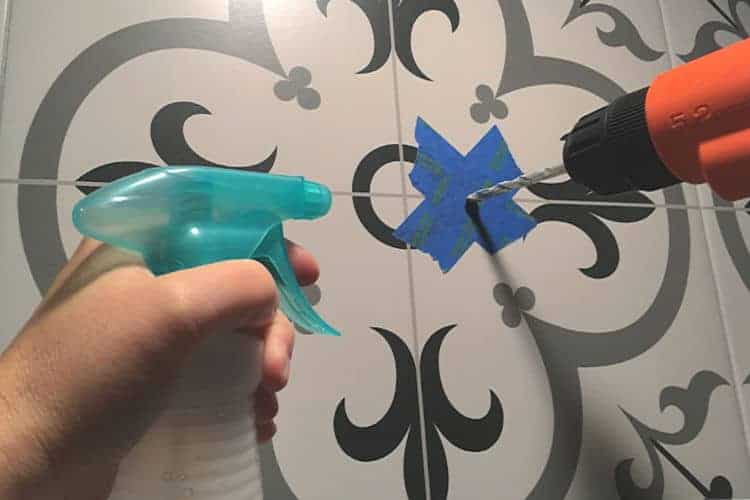 Spraying water while drilling into tile, to keep from breaking the tile from the heat of the drill.