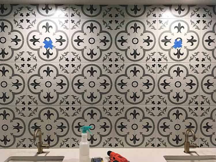 Patterned tile backsplash before hanging mirrors. Blue tape marks the spot.