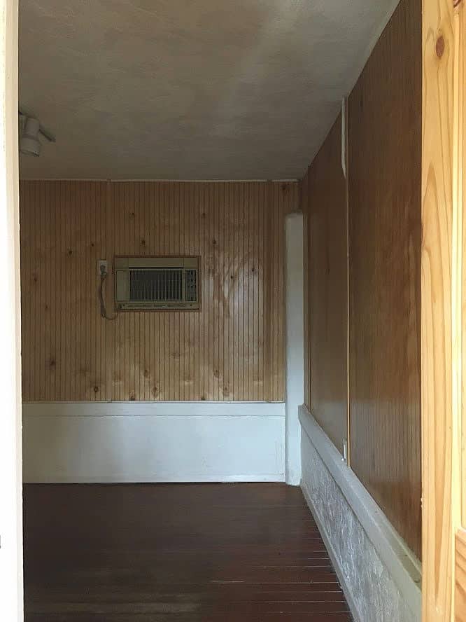 Small dark room with wood paneling and no windows