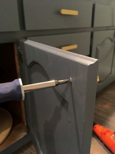 Screwing on the cabinet hardware from the back of the door