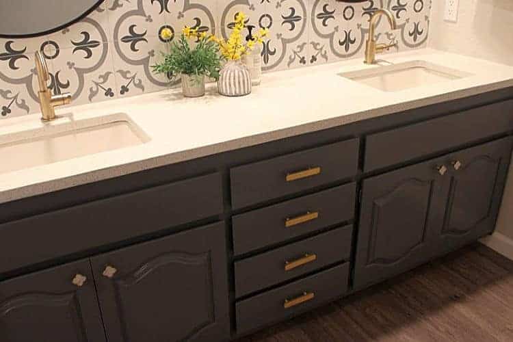 Brass cabinet hardware on a dark gray bathroom vanity