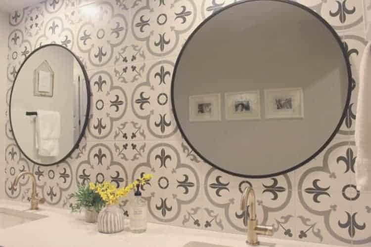 Round mirror hanging on patterned tile backsplash