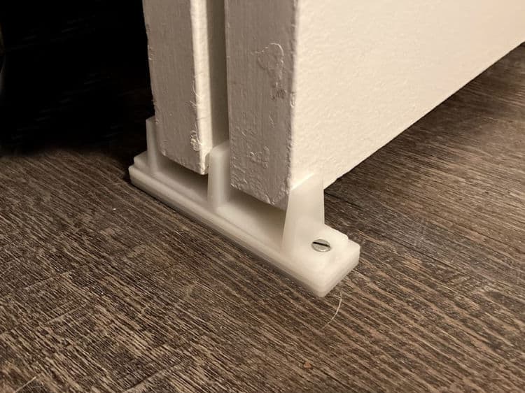 White plastic floor guide for two sliding closet doors.