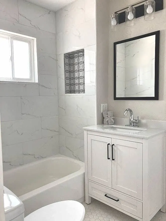 Small white bathroom with white vanity and white marble tile in the shower.