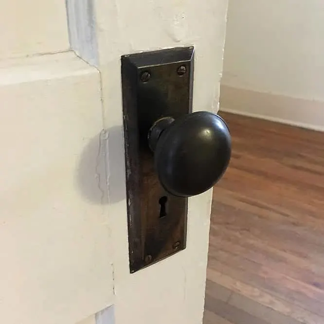 White door with historic dark bronze door handle and plate complete with keyhole