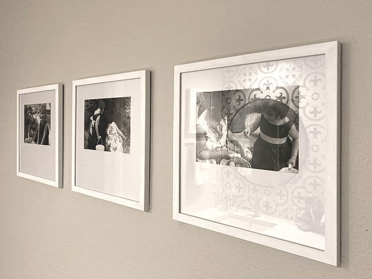 Three black and white photos in white frames, hung in a row