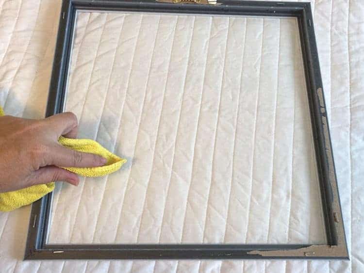 using a microfiber cloth to dust the glass of a frame