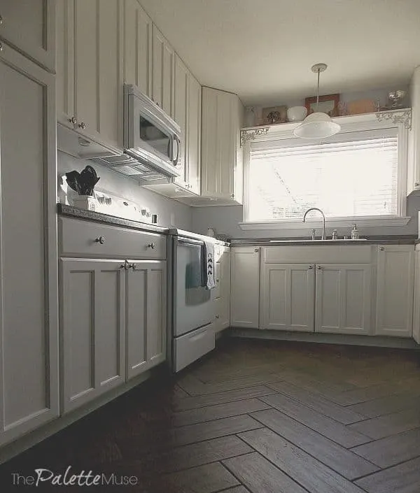 White kitchen cabinets on dark wood floor.