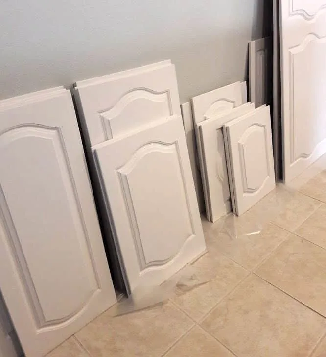 White painted cabinet doors leaning against the wall to dry