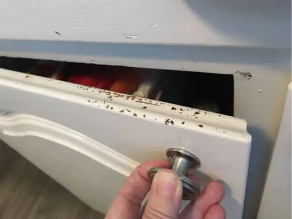 White painted cabinet shows chips in the paint on a well-used edge.