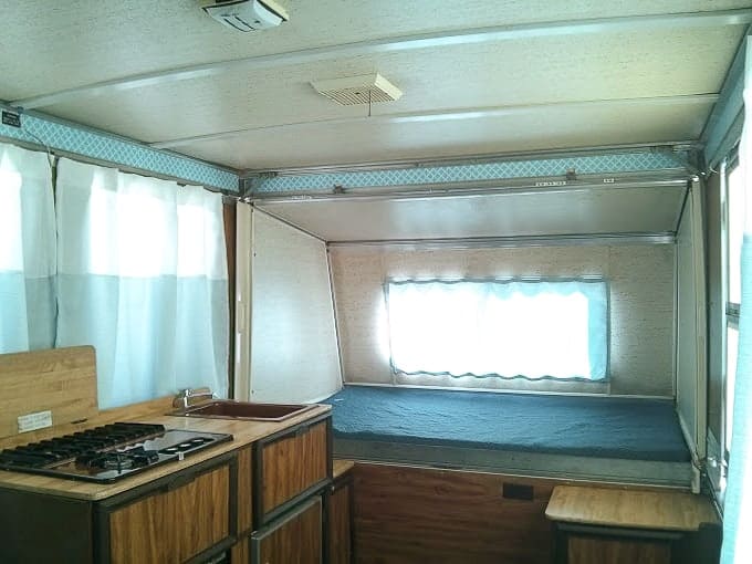 Blue curtains line the interior of an Apache camper