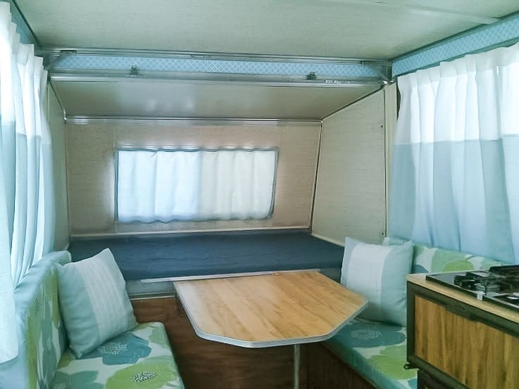 Apache camper interior with blue curtains and cushions