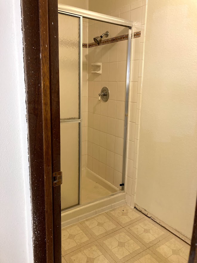 Dated shower area with cheap linoleum flooring