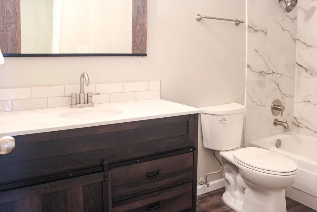 Flip House Before and After Modern bathroom with dark wood vanity and white marble tile