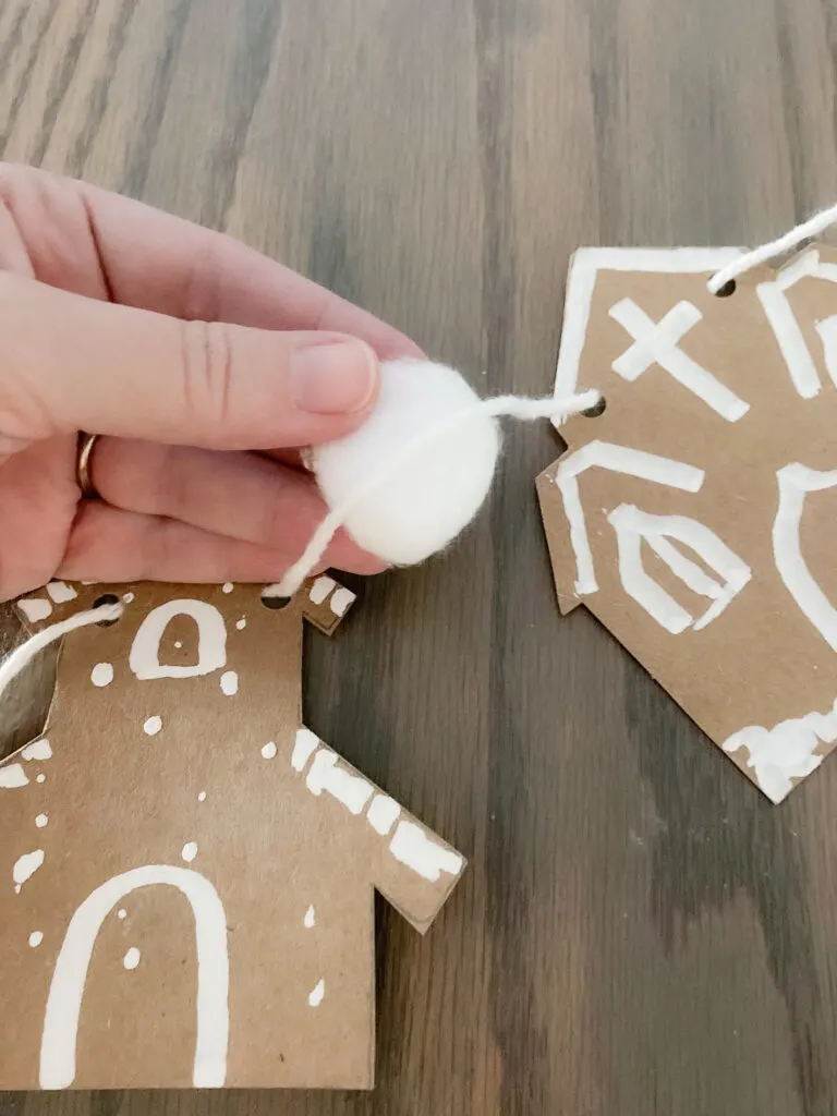 Gluing cotton balls to the string of a gingerbread house banner