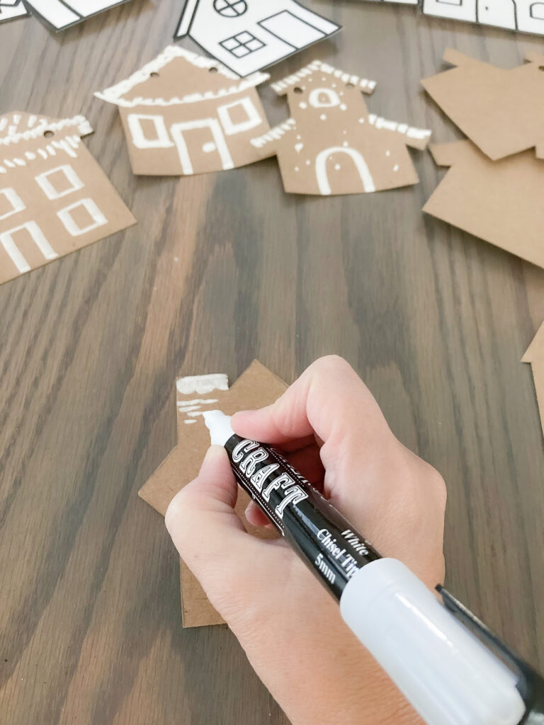 Using a chalk marker to paint a brown paper house shape to look like a gingerbread house
