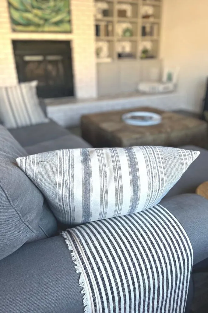 A gray and white striped pillow and blanket on a gray couch.