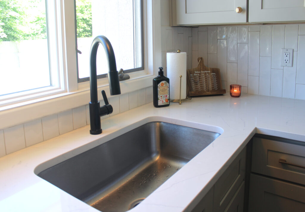 stainless steel kitchen sink with white countertops and black faucet