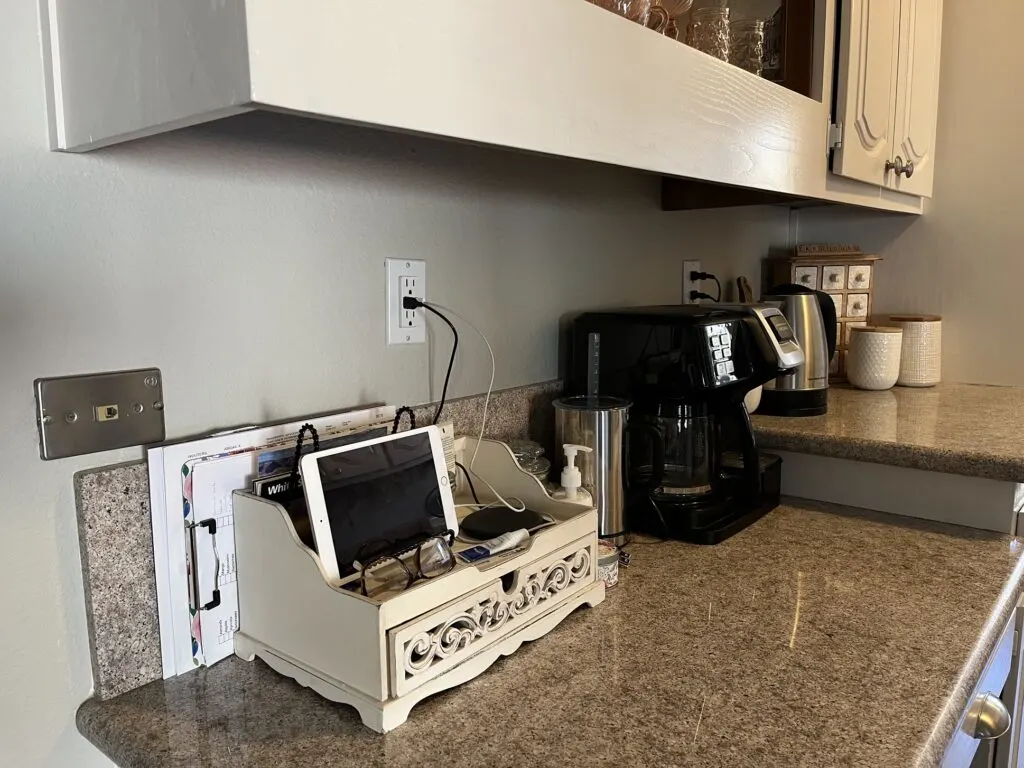 A view of a countertop with a charging station on top and several wires coming from it to the wall outlet.