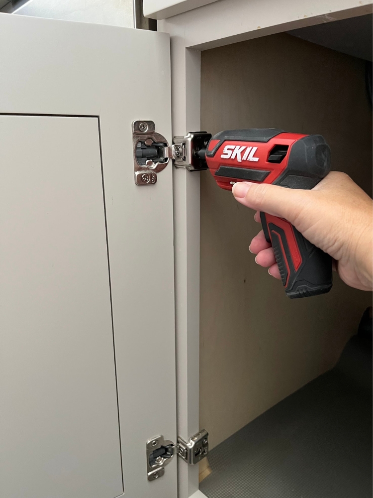 Removing cabinet door hinges with a Skil electric screwdriver