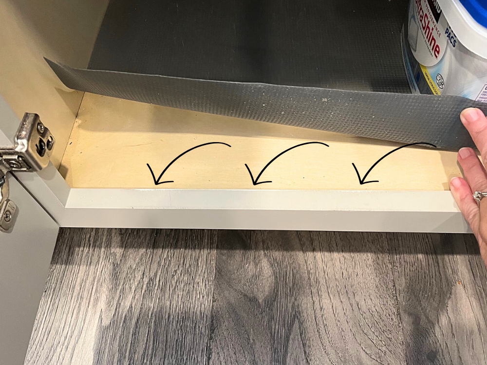 Arrows pointing to scuff marks on the cabinet frame where the trash bin has been pulled out and put back too many times.