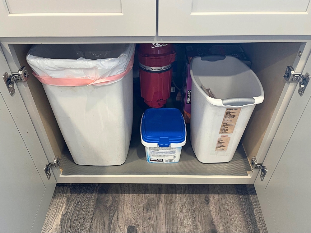 Under sink cabinet organization with trash cans and shelf liner.