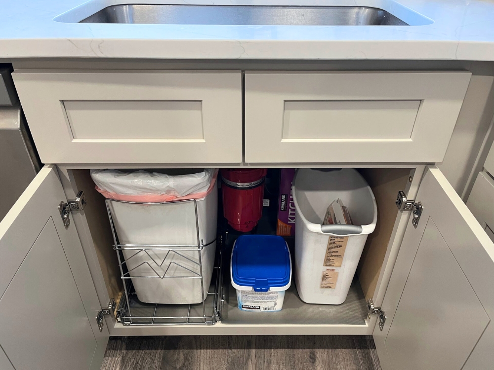 Under sink cabinet organization with a slim trash pull out system in place.
