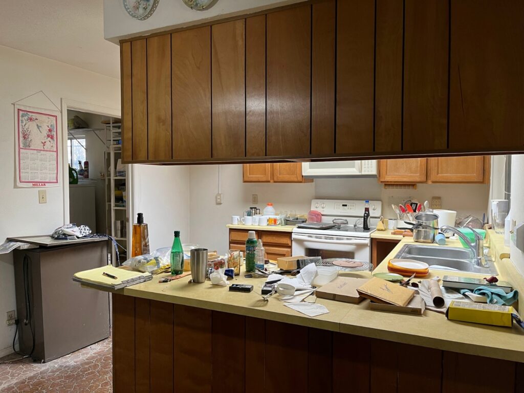 A cluttered kitchen with upper cabinets getting in the way.